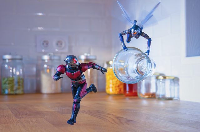 An Ant-Man figure running across a kitchen counter while the Wasp flies off with a glass jar
